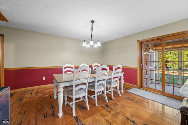 dining room with a notable chandelier, a textured ceiling, and hardwood / wood-style floors