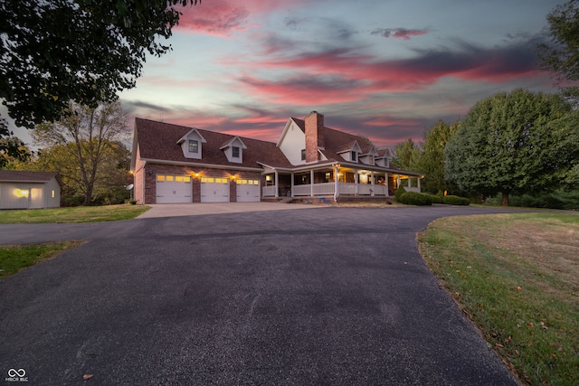 view of front of property featuring covered porch, a lawn, and a garage