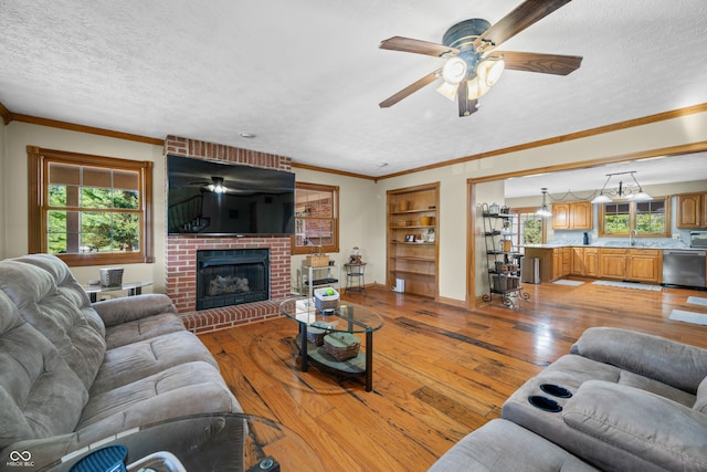 living room with a textured ceiling, a wealth of natural light, light wood-type flooring, and a fireplace