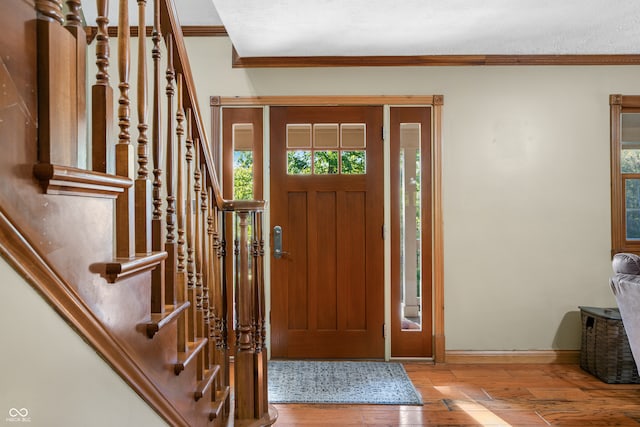 foyer entrance featuring a healthy amount of sunlight, crown molding, a textured ceiling, and light hardwood / wood-style floors