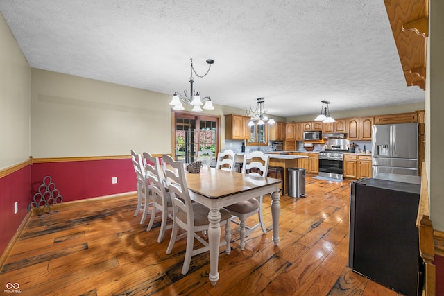 dining room with a chandelier, a textured ceiling, and dark hardwood / wood-style flooring