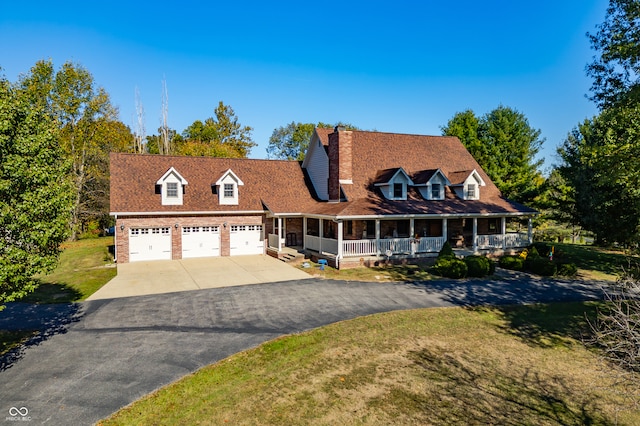 view of front of property featuring covered porch, a garage, and a front lawn