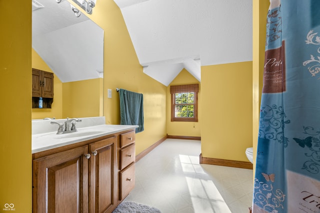 bathroom with vanity, toilet, a textured ceiling, and vaulted ceiling