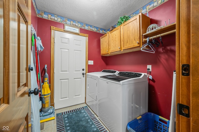 clothes washing area featuring a textured ceiling, washing machine and dryer, and cabinets