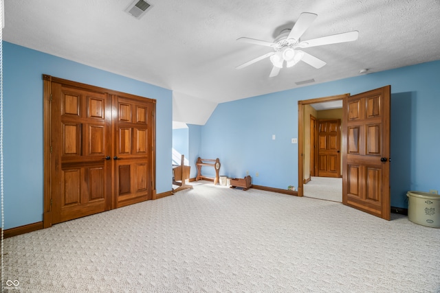 interior space featuring ceiling fan, a textured ceiling, carpet floors, and vaulted ceiling