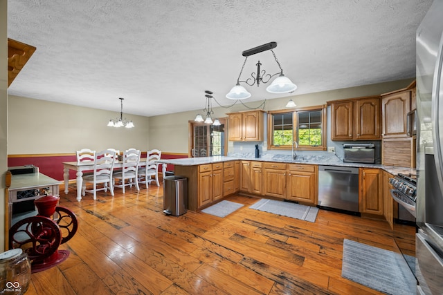 kitchen with hardwood / wood-style flooring, appliances with stainless steel finishes, an inviting chandelier, and hanging light fixtures