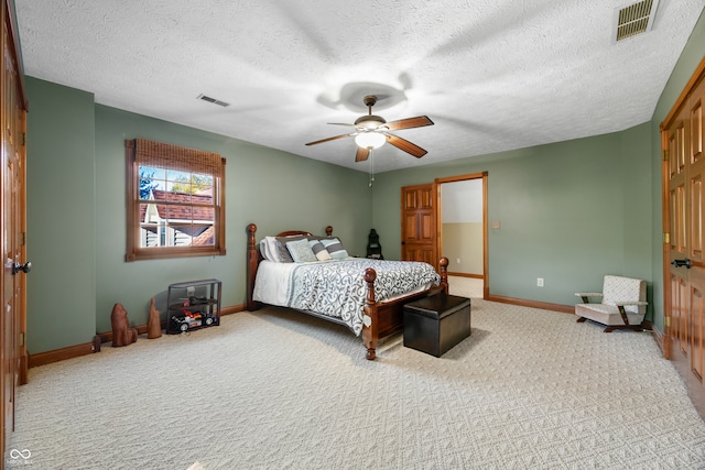 bedroom with a textured ceiling, light colored carpet, and ceiling fan