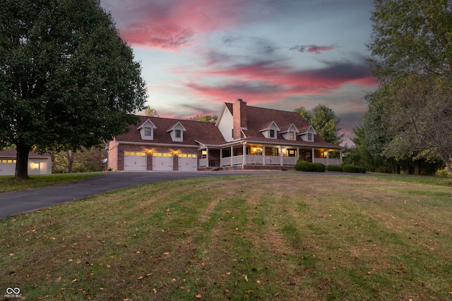 new england style home featuring covered porch and a yard