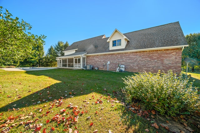 back of property with a sunroom, a lawn, and cooling unit