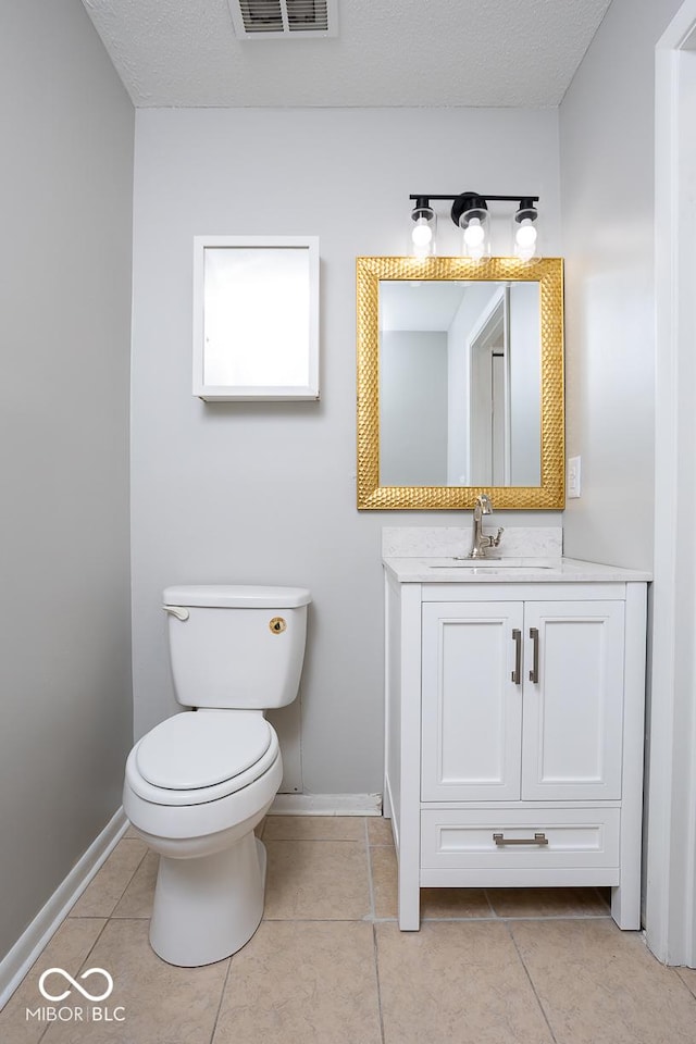 bathroom featuring vanity, toilet, tile patterned flooring, and a textured ceiling