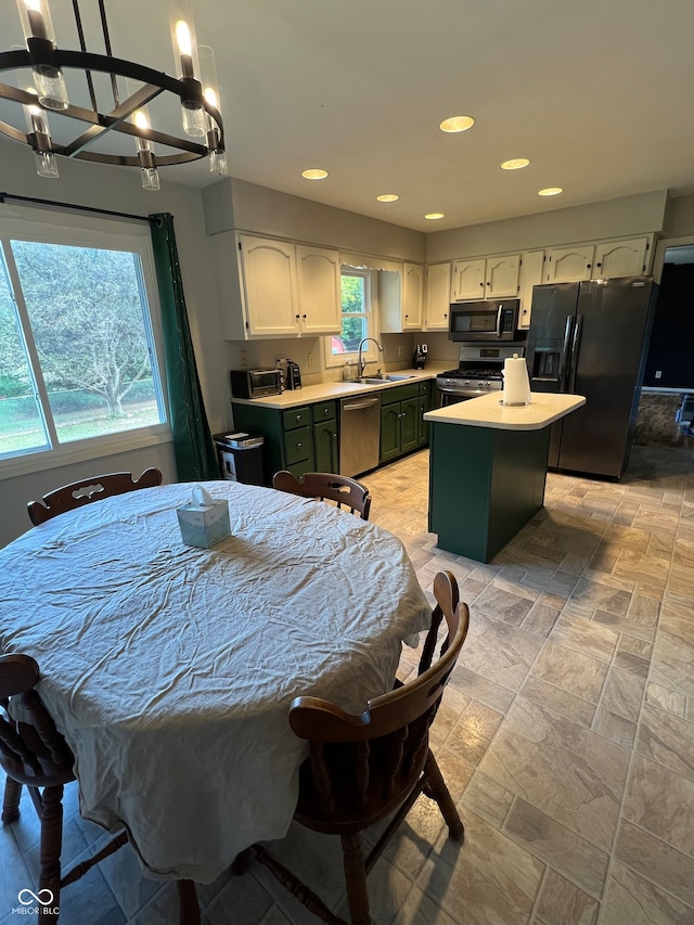 kitchen featuring a notable chandelier, green cabinetry, sink, black appliances, and a center island