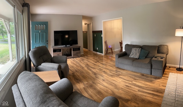 living room with a wealth of natural light, vaulted ceiling, and light hardwood / wood-style flooring