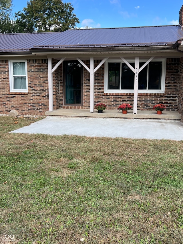 entrance to property with a patio area and a lawn