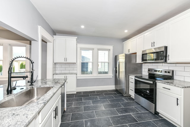 kitchen featuring a wealth of natural light, white cabinetry, sink, and appliances with stainless steel finishes