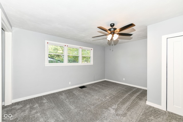 unfurnished room featuring ceiling fan and dark carpet