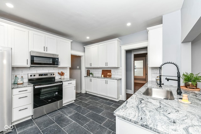 kitchen with light stone countertops, sink, stainless steel appliances, tasteful backsplash, and white cabinets