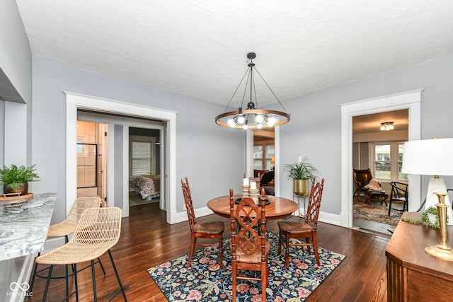 dining room featuring dark wood-type flooring, a textured ceiling, and an inviting chandelier