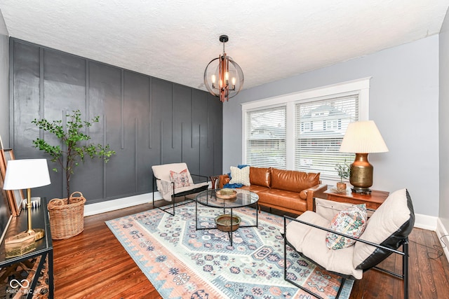 living room with a notable chandelier, wood-type flooring, and a textured ceiling