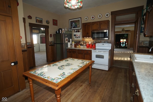 kitchen with ceiling fan, black fridge, sink, electric stove, and hardwood / wood-style flooring