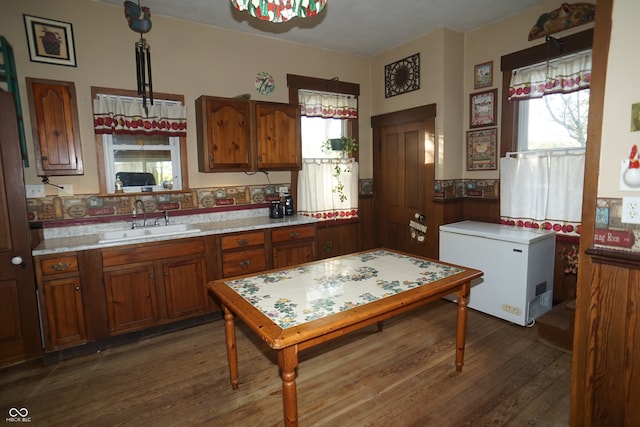 kitchen with hanging light fixtures, dark hardwood / wood-style floors, sink, and refrigerator