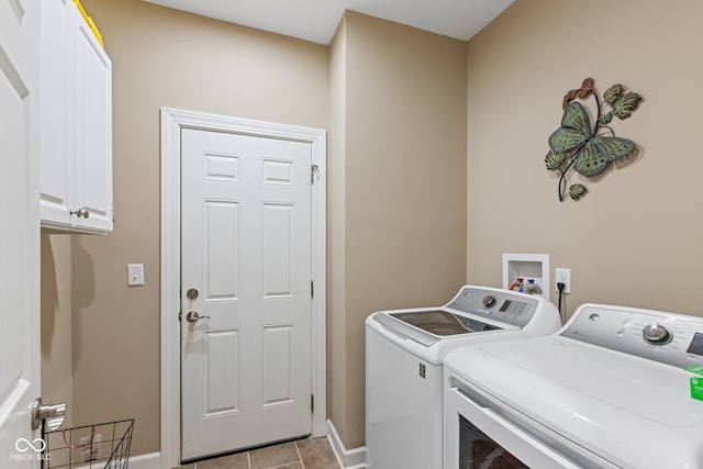 clothes washing area with light tile patterned flooring, washing machine and clothes dryer, and cabinets