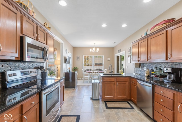 kitchen featuring tasteful backsplash, appliances with stainless steel finishes, sink, decorative light fixtures, and a notable chandelier