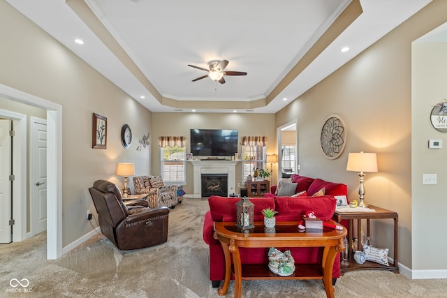 living room with crown molding, a raised ceiling, carpet flooring, and ceiling fan