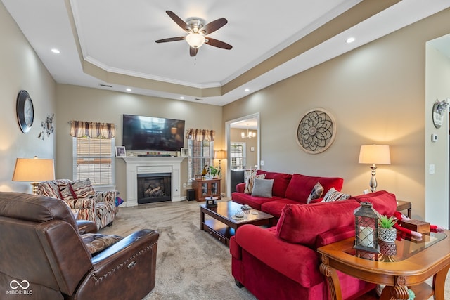 carpeted living room featuring ornamental molding, ceiling fan, and a raised ceiling