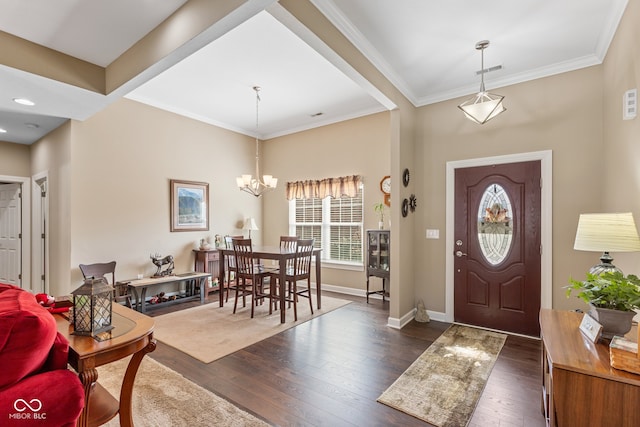 foyer with ornamental molding, dark hardwood / wood-style floors, and an inviting chandelier