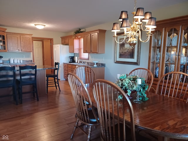 dining room with sink, dark hardwood / wood-style floors, and an inviting chandelier