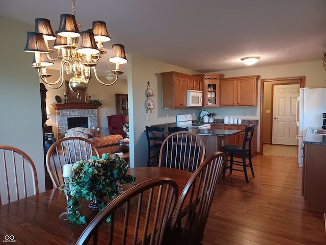 dining area featuring a notable chandelier, a brick fireplace, and hardwood / wood-style floors