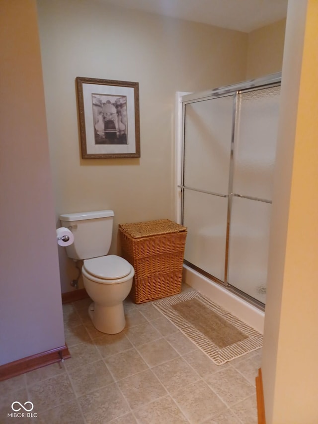 bathroom featuring tile patterned floors, a shower with shower door, and toilet