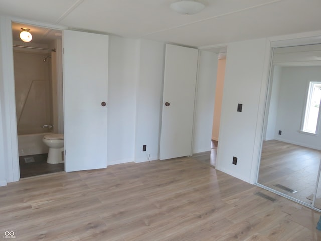 unfurnished bedroom featuring light hardwood / wood-style flooring and ensuite bath