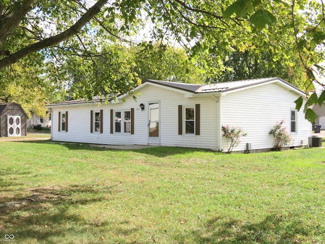 rear view of property with a storage shed, a lawn, and central AC unit