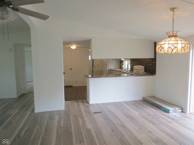 kitchen with vaulted ceiling, hanging light fixtures, and wood-type flooring