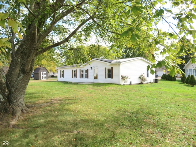 back of property with a shed and a yard