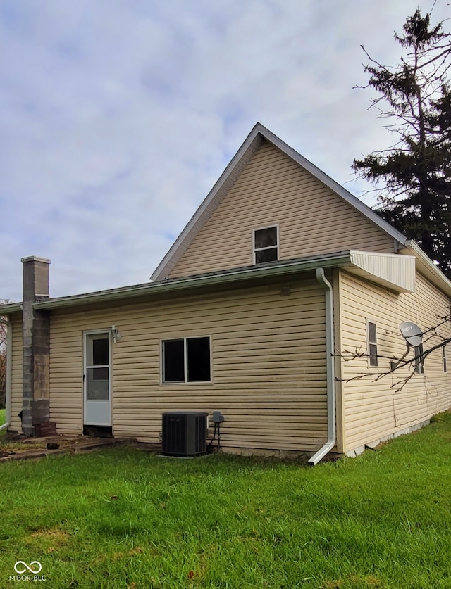 rear view of property with cooling unit and a lawn