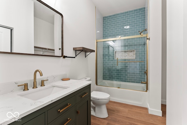 full bathroom with vanity, toilet, wood-type flooring, and combined bath / shower with glass door