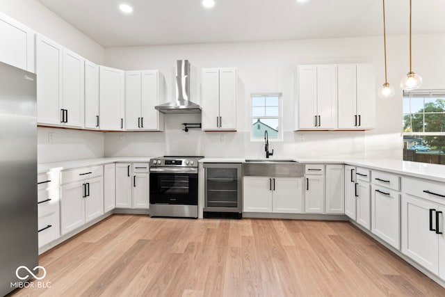 kitchen with wall chimney range hood, a healthy amount of sunlight, sink, and appliances with stainless steel finishes