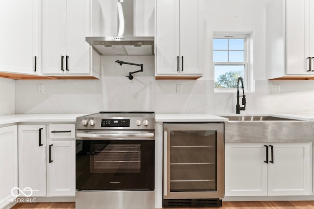 kitchen featuring white cabinetry, wall chimney exhaust hood, wine cooler, and stainless steel range with electric cooktop