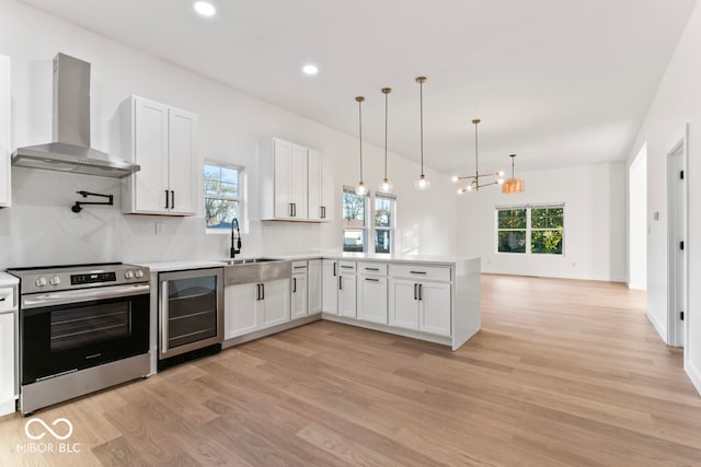 kitchen with stainless steel range with electric stovetop, white cabinetry, wine cooler, and wall chimney range hood