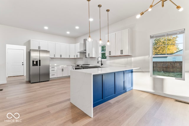 kitchen with kitchen peninsula, stainless steel appliances, pendant lighting, and white cabinets