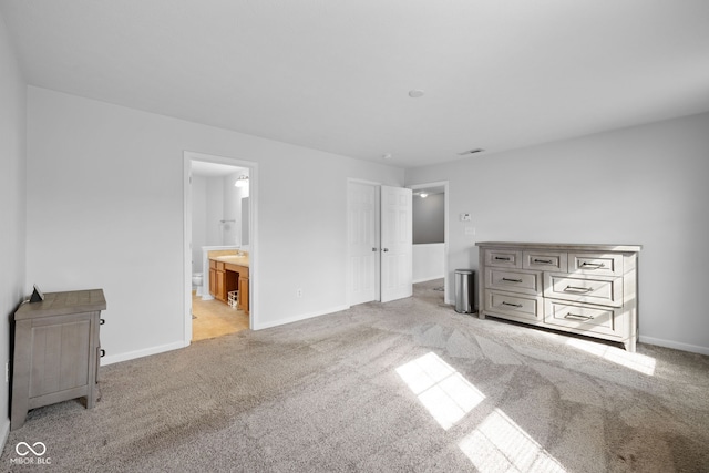 unfurnished bedroom featuring ensuite bathroom and light colored carpet