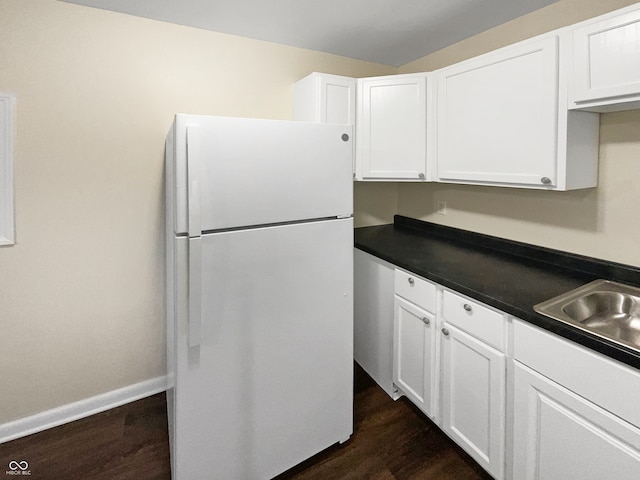 kitchen with white cabinets, white refrigerator, sink, and dark wood-type flooring