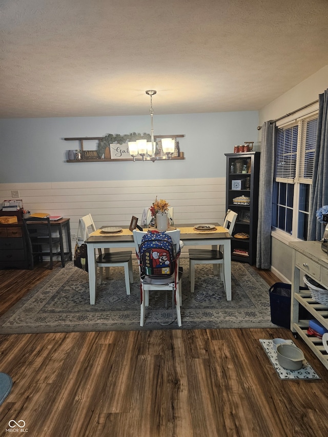 dining space with dark wood-type flooring, a textured ceiling, and a chandelier