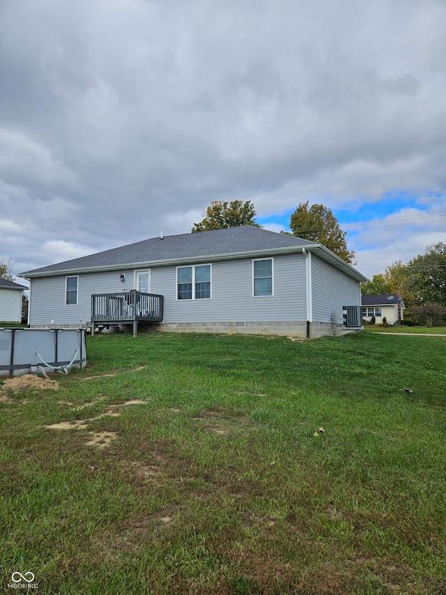 rear view of property with a wooden deck and a lawn