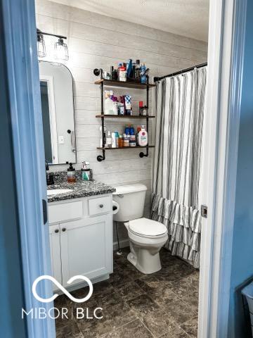 bathroom with vanity, wood walls, a shower with curtain, and toilet