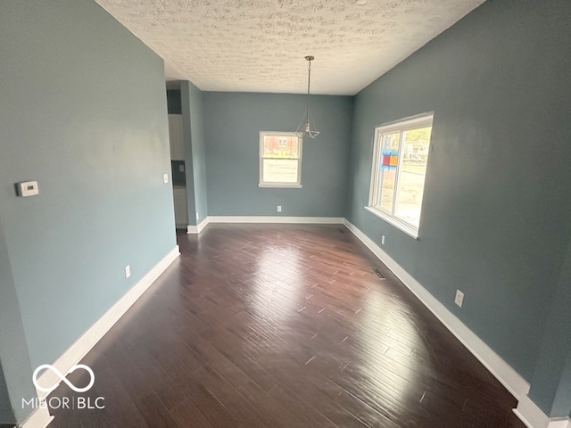 spare room featuring a textured ceiling and dark wood-type flooring