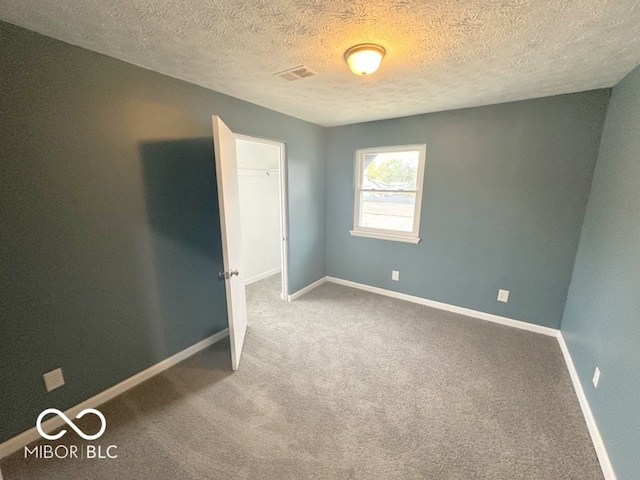 carpeted spare room featuring a textured ceiling