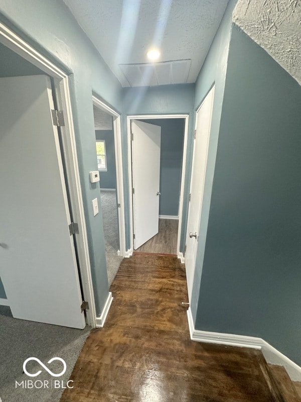 corridor featuring a textured ceiling and dark hardwood / wood-style flooring